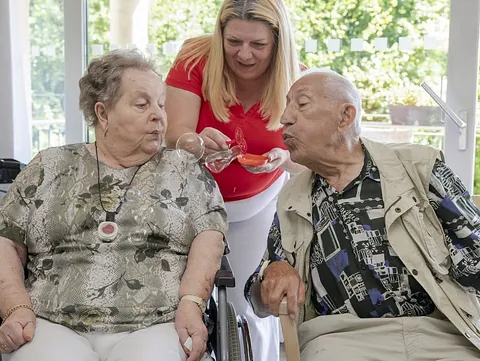 Zwei ältere Menschen machen Seifenblasen.