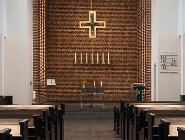 Eine Kirche von innen, man sieht den Altar und ein goldenes Silhouettenkreuz.